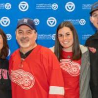 A family of four standing together by the Alumni Relations backdrop.